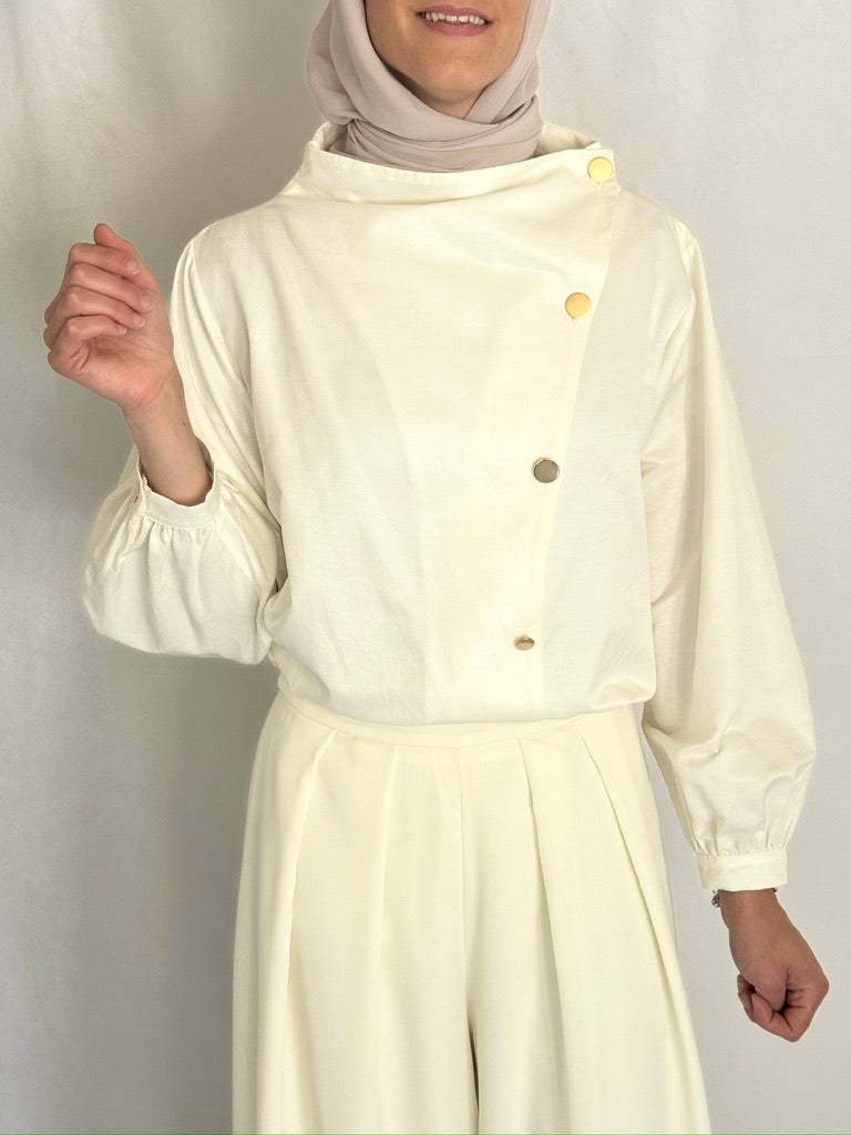 Closeup look of the ivory shirt with gold buttons.