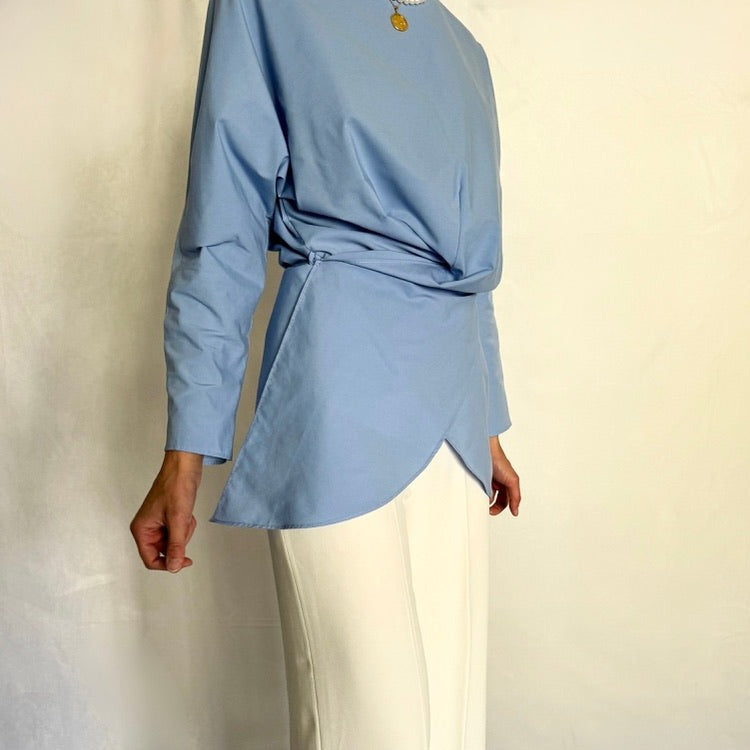 closeup look to the blue tied wrap tunic paired with white trousers