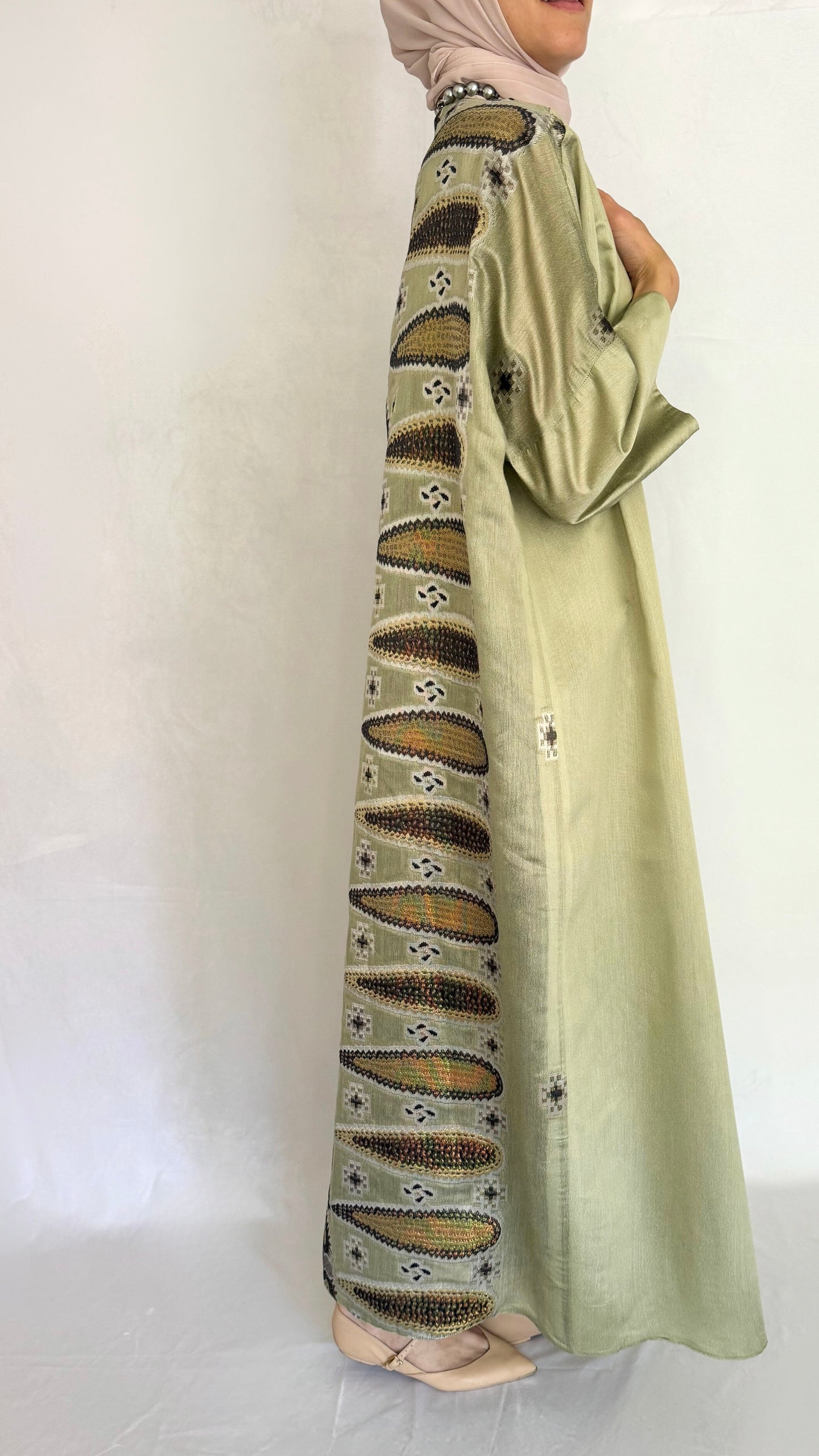 side view of the pistachio abaya that shows the back pattern. 